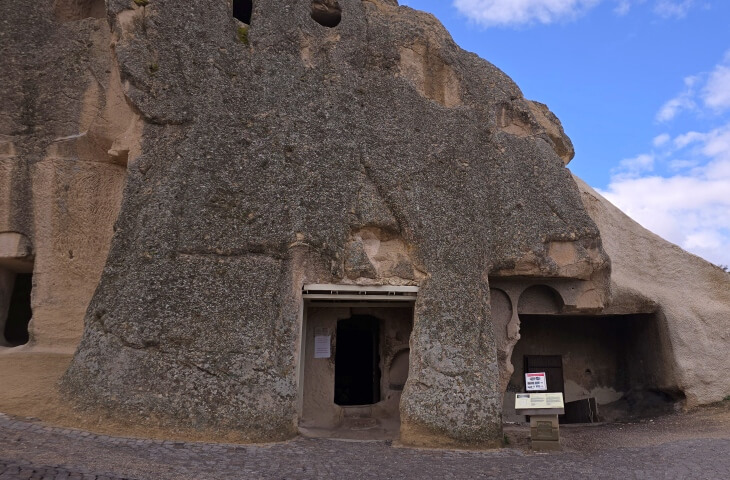 Göreme Açık Hava Müzesi’ndeki Yılanlı Kilise’nin dış cephesi ve kaya oyma girişi, bilgilendirme tabelasıyla birlikte görülüyor.